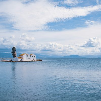 Panorama di Corfù visto dal mare, con cielo nuvoloso e mare calmo alle spalle del monastero